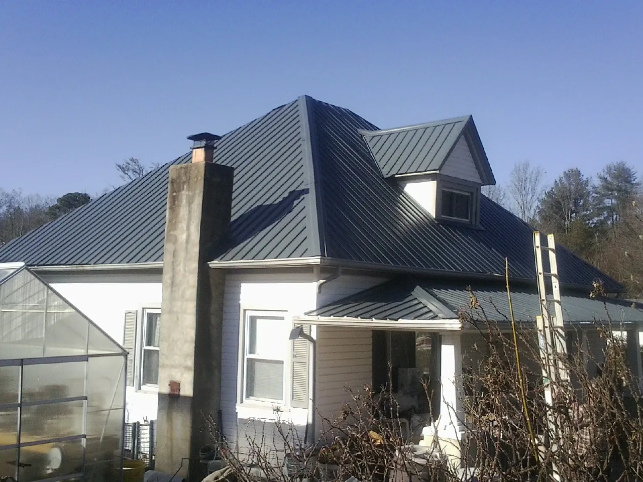 Dark blue standing seam metal roof on a white farmhouse with dormer — Slate & Tile Roof Repair by Roofing Brothers in Morrow
