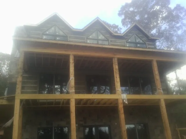 Dormers and porch framing on a large log home under construction — Roof Coating work by our crew in Morrow